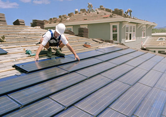 MAN INSTALLING SOLAR PANELS ON THE ROOF